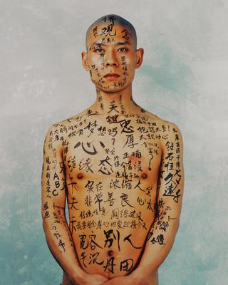 head, torso and arms of a man with Chinese characters written in black on his face, arms and body